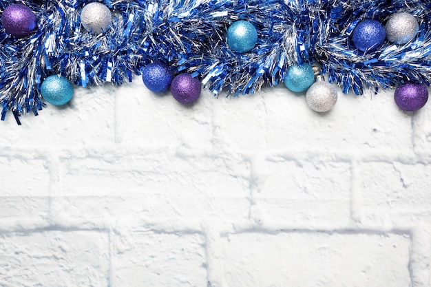 Moldura de Natal feita de decorações de enfeites de Natal guirlanda em prata e azul sobre um fundo de tijolo claro. Copie o espaço. Postura plana.