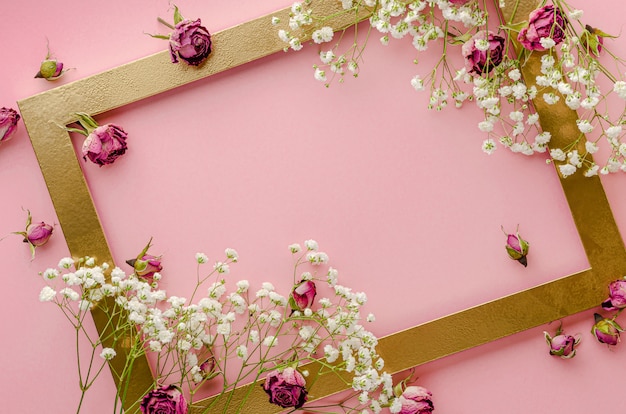Moldura dourada criativa decorada com conceito de cartão de rosas cor de rosa secas. Configuração plana, cópia espaço
