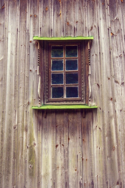 Moldura esculpida e janela na velha casa de madeira de tábuas
