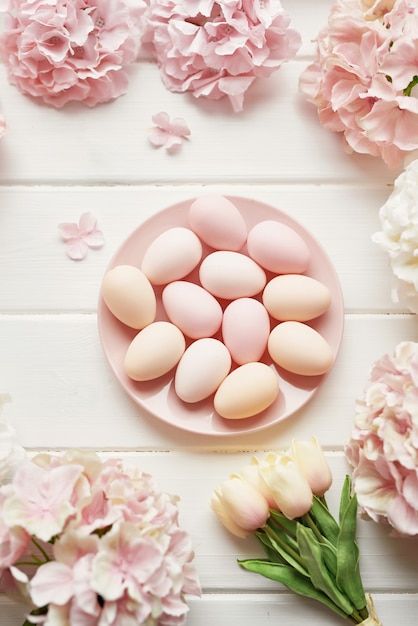 Moldura feita de flores de hortênsia rosa e bege, ovos cor de rosa e tulipas amarelas