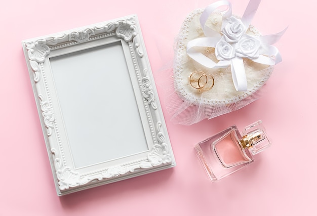 Foto moldura para fotos e anéis de ouro em um frasco de perfume branco para o aniversário de casamento