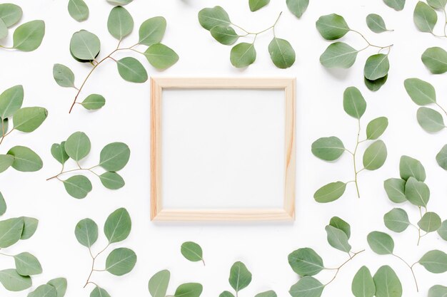 Moldura quadrada decorada com eucalipto verde deixa padrão floral de galhos em um fundo branco o a