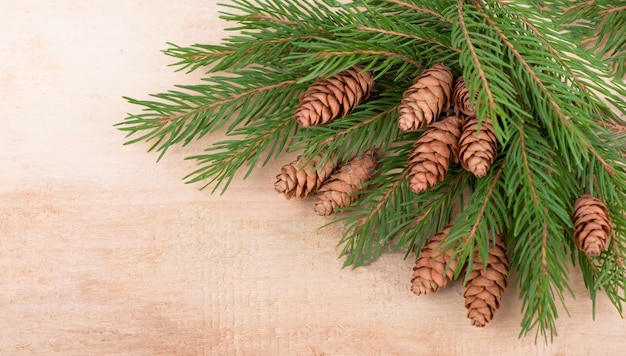 Moldura rústica decorativa de Natal com ramos de abeto e cones em fundo escuro de madeira, copyspace para seu texto