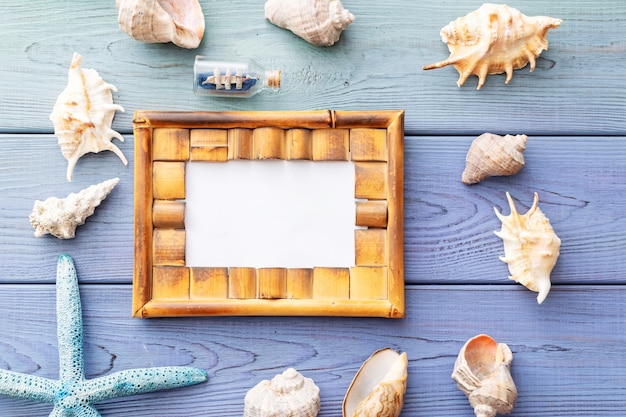Molduras para fotos de fundo de verão, conchas, coral, navio em uma garrafa em um fundo azul de madeira