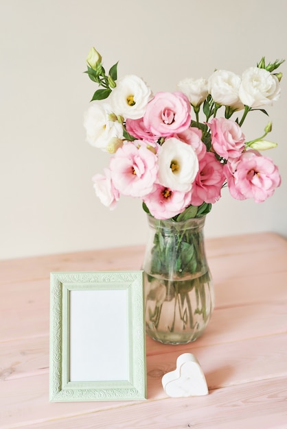 Molduras para fotos e flores em um vaso na mesa