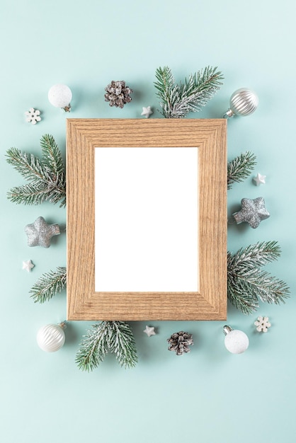 Molduras para fotos em branco de natal ou feliz ano novo com galhos de árvores de abeto, decorações do feriado em fundo azul. postura plana. brincar. vista do topo. orientação vertical