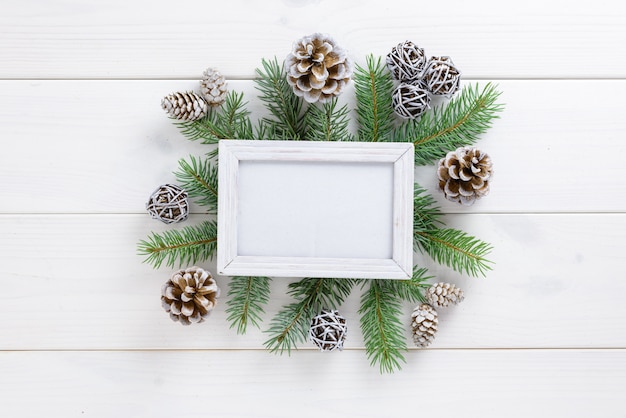 Molduras para fotos entre a decoração de Natal, com pinhas em uma mesa de madeira branca. Vista superior, moldura para copiar o espaço