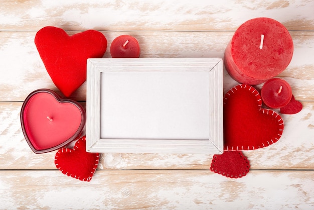 Molduras para fotos entre a decoração romântica do dia dos namorados com coração e vela em uma mesa de madeira branca