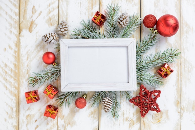 Foto molduras para fotos entre decoração de natal, com bolas vermelhas e caixa de presente em uma mesa de madeira branca. vista superior, moldura para copiar o espaço