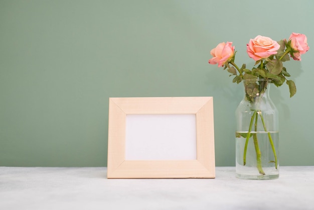 Molduras para fotos para texto com um vaso com rosas em uma mesa cinza e fundo verde