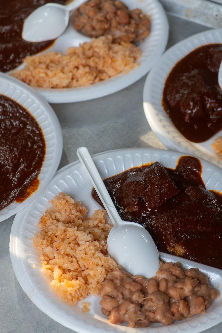Foto mole rojo autêntico com arroz e feijão refritado em pratos descartáveis no méxico