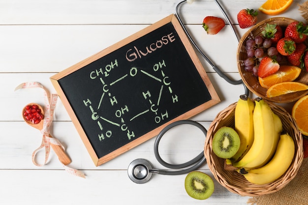 Molécula de glucosa en pizarra con frutas frescas mixtas