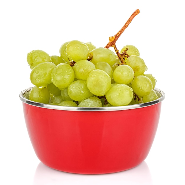 Molhe cacho de uvas verdes com gotas de água em uma tigela de metal vermelha isolada no branco