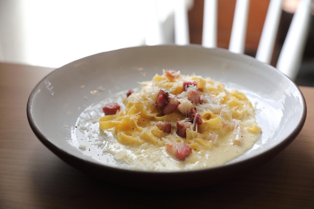 Molho branco de espaguete carbonara com bacon em fundo de madeira no restaurante