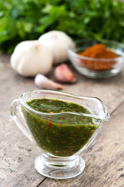 Molho de Chimichurri verde e ingredientes na mesa de madeira