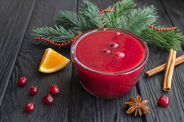 Molho de cranberry na tigela de vidro sobre a mesa de madeira preta