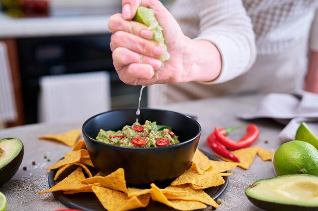 Foto molho de guacamole com chips de tortilha ou nachos na tábua de servir preta