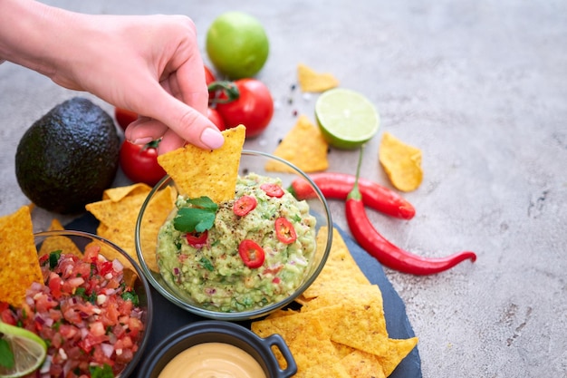 Molho de molho de salsa e guacamole feito na hora com chips de nacho na tábua de servir de pedra