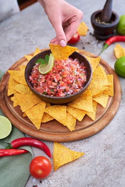 Foto molho de molho de salsa feito na hora com chips de nacho na placa de madeira