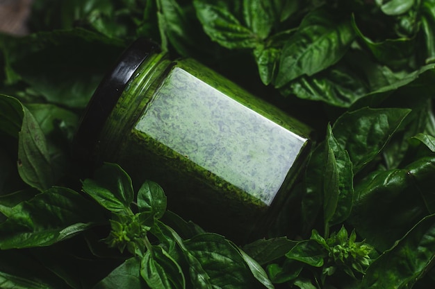 Molho de pesto em um frasco de vidro folhas de manjericão verde