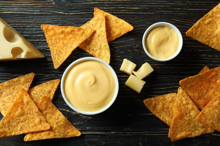 Molho de queijo, queijo e batatas fritas em mesa de madeira rústica