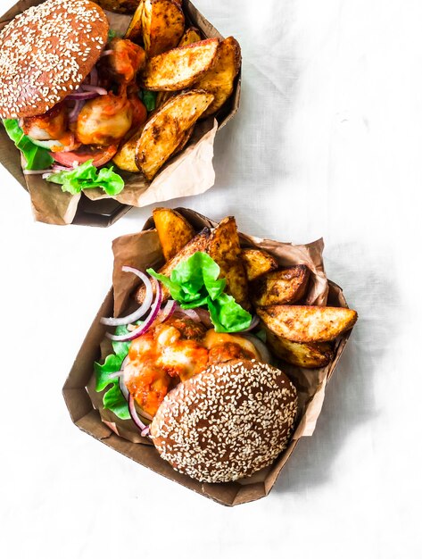 Molho de tomate almôndegas queijo mussarela pães integrais hambúrgueres e batatas assadas em uma vista superior de fundo claro