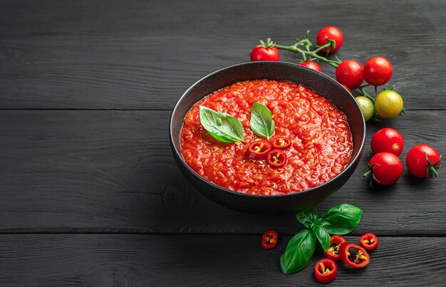 Molho de tomate caseiro com manjericão em um fundo preto. Vista lateral, copie o espaço