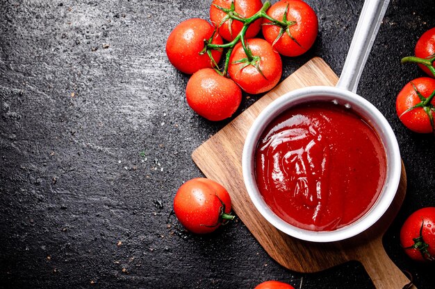 Foto molho de tomate com rolo de molho em uma tábua de madeira