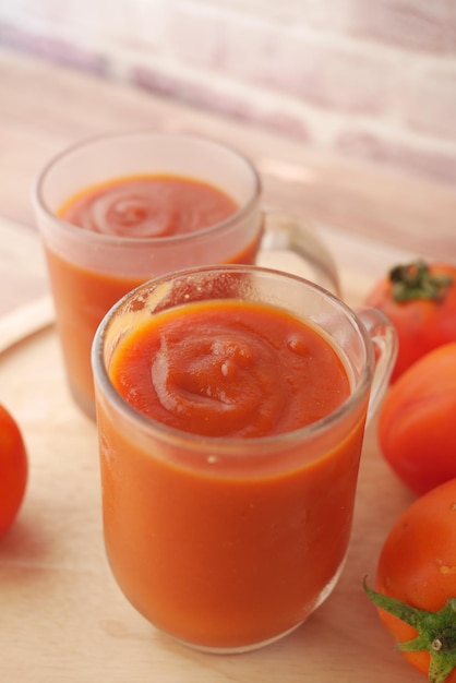 Molho de tomate em uma jarra com tomate fresco na mesa