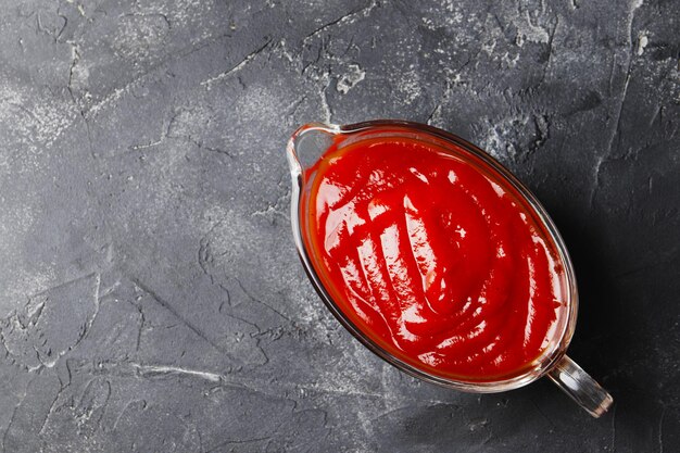 Foto molho de tomate em uma molheira em um fundo escuro