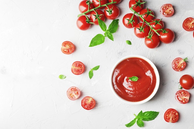 Foto molho de tomate em uma tigela manjericão fresco e tomate cereja fresco ingredientes para o molho ingredientes para cozinhar