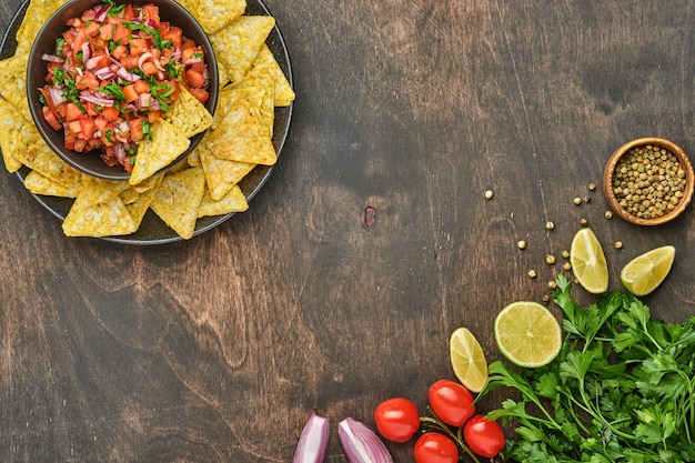 Molho de tomate mexicano tradicional com nachos e tomates de ingredientes, pimenta, alho, cebola no fundo escuro de madeira velho. conceito de comida latino-americana e mexicana. brincar.