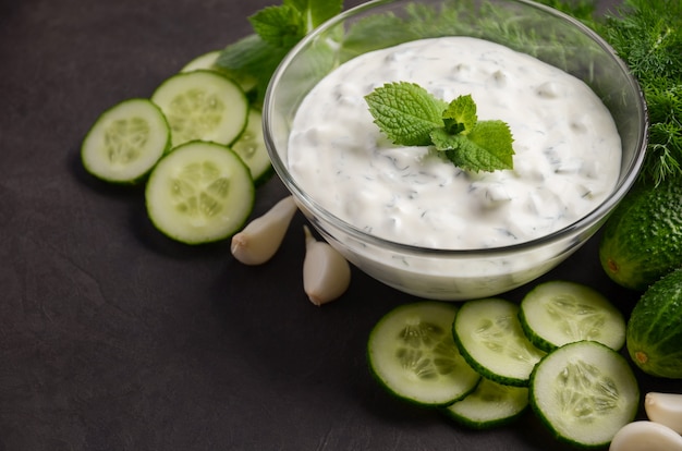 Molho de tzatziki e ingredientes no escuro.