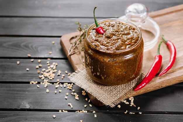 Molho misto com diferentes ervas picantes em tigela de vidro com fundo de madeira