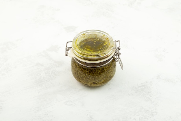 Molho pesto de manjericão em jarra Molho pesto de manjericão italiano tradicional com pinhões de parmesão e azeite