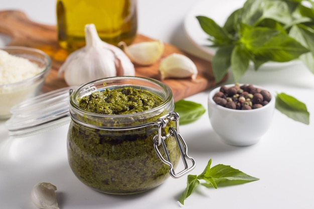 Molho pesto de manjericão em uma jarra. ingredientes para cozinhar, queijo, parmesão, alho, azeite.