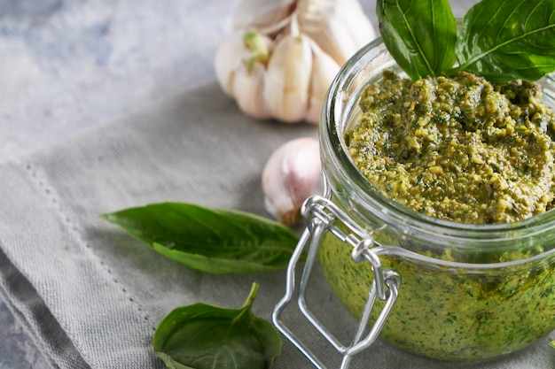 Molho pesto de manjericão italiano tradicional em uma jarra de vidro sobre uma mesa de pedra clara