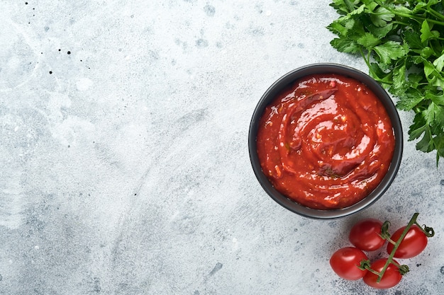Molho picante de ketchup de tomate com ingredientes de salsa, alho e pimenta em uma tigela preta