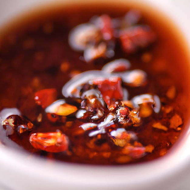 Foto molho picante de pimenta vermelha seca com óleo de soja em uma tigela branca fechada