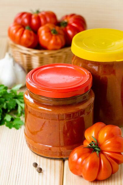 Foto molho picante de tomate caseiro com alho e pimenta em potes de vidro na mesa de madeira.