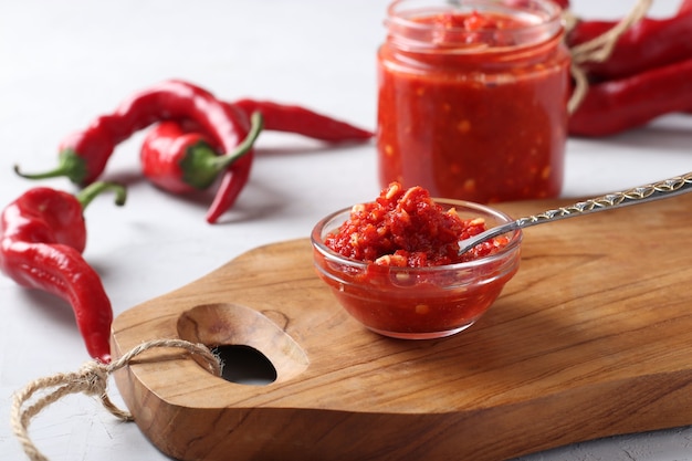 Molho tradicional adjika com pimenta malagueta, cole harissa em uma tigela na placa de madeira. Fechar-se