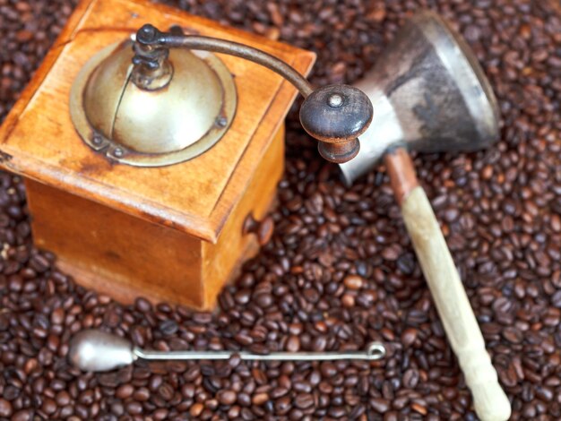 Foto molinillo de café y olla de cobre sobre frijoles tostados