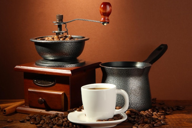 Molinillo de café turco y taza de café sobre fondo marrón
