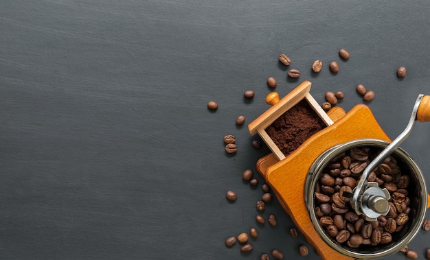 Molinillo de mano y grano de café sobre mesa negra