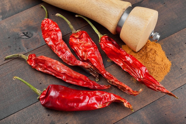 Molinillo de pimienta de pimientos rojos y montón de tierra fría en la mesa de madera