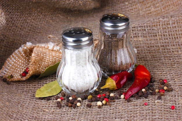 Foto molinillos de sal y pimienta y especias sobre arpillera