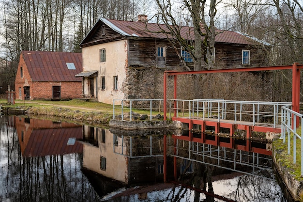 Molino de agua en la orilla del lago y su reflejo en la superficie del agua