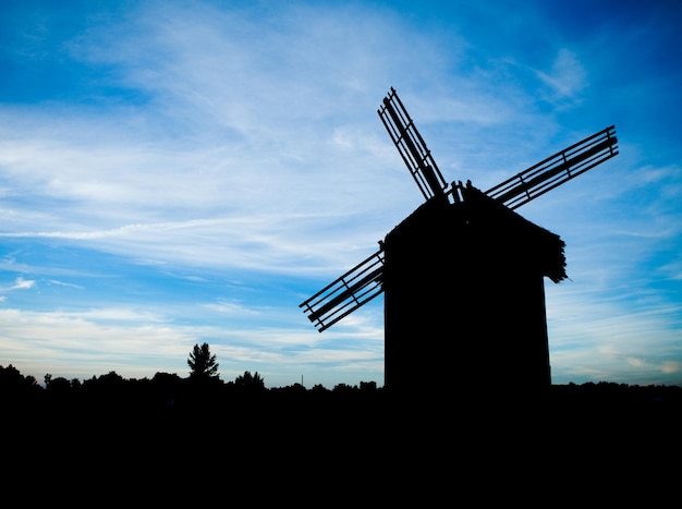 Molino de viento en el campo y cielo nublado azul