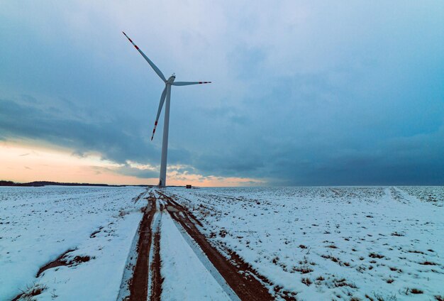 Molino de viento en un campo nevado con un cielo nublado en el fondo