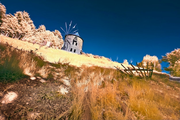 un molino de viento está en una colina con un cielo azul en el fondo